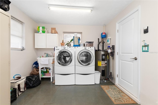 clothes washing area featuring cabinets, washing machine and clothes dryer, and electric water heater