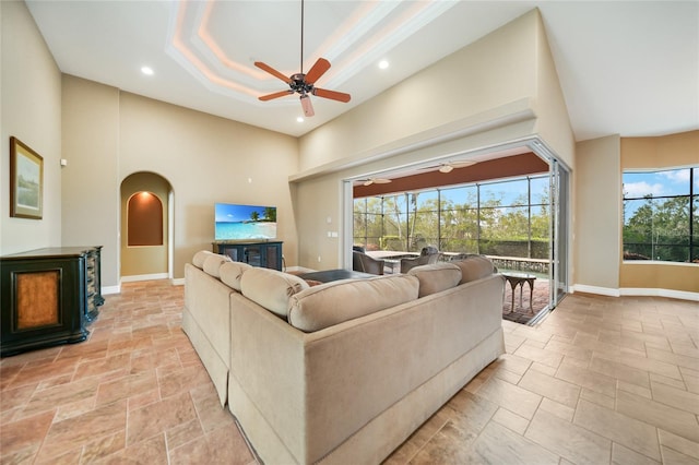 living room featuring ceiling fan, a healthy amount of sunlight, a towering ceiling, and a tray ceiling