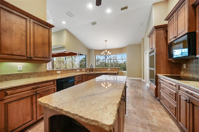 kitchen featuring light stone counters, black appliances, a center island, and a healthy amount of sunlight