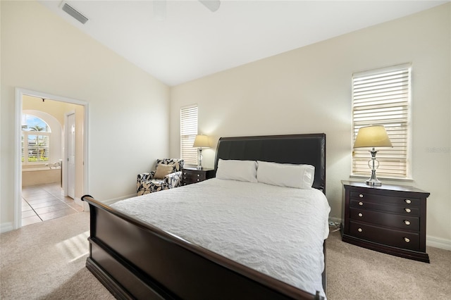 bedroom with ensuite bathroom, ceiling fan, light carpet, and lofted ceiling