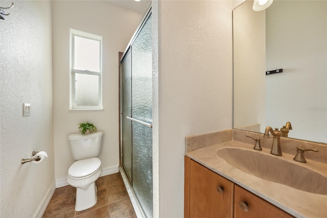 bathroom featuring toilet, vanity, and a shower with shower door