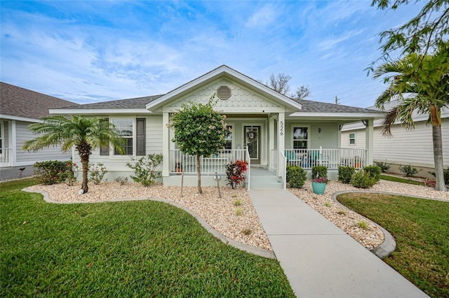 ranch-style home featuring covered porch and a front lawn