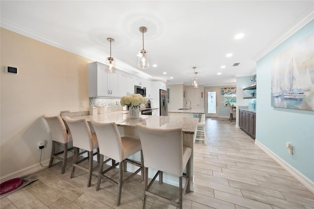 kitchen featuring white cabinetry, stainless steel appliances, pendant lighting, and kitchen peninsula