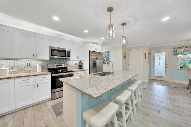 kitchen featuring sink, hanging light fixtures, white cabinets, and stainless steel appliances