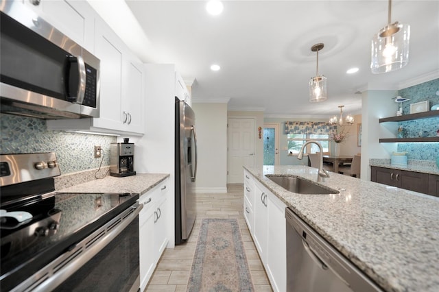 kitchen with light stone countertops, pendant lighting, appliances with stainless steel finishes, white cabinetry, and sink