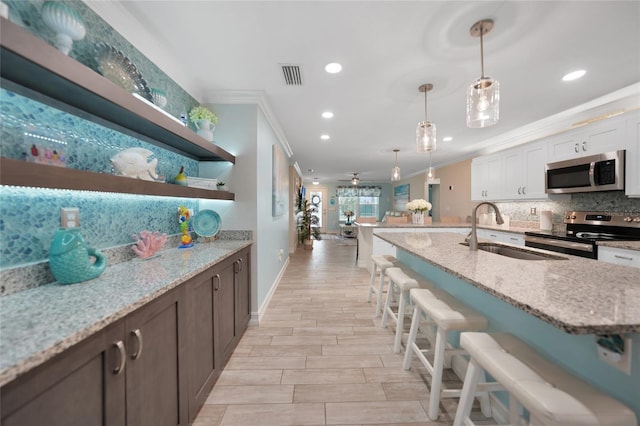 kitchen featuring light stone countertops, pendant lighting, white cabinetry, stainless steel appliances, and sink