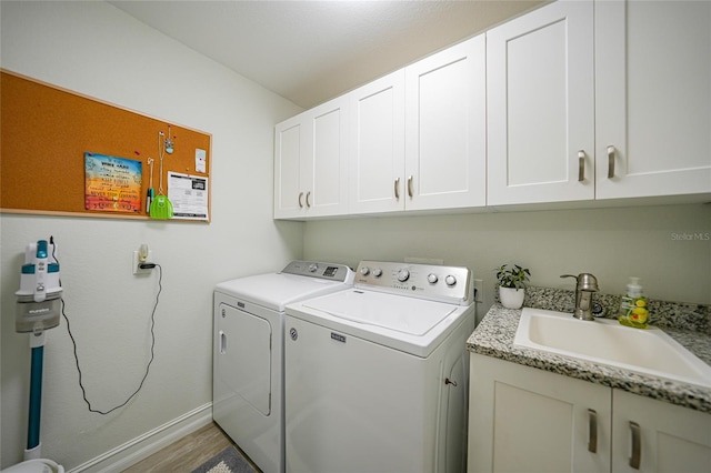 laundry room with washer and clothes dryer, sink, light hardwood / wood-style floors, and cabinets