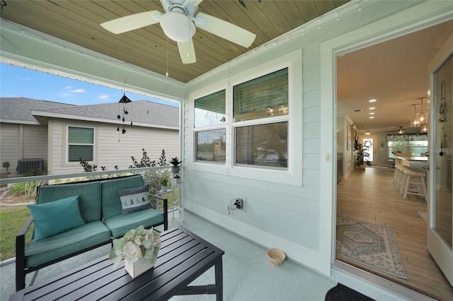 wooden terrace with an outdoor hangout area, ceiling fan, and central AC