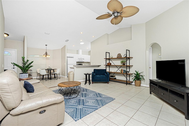 tiled living room with ceiling fan with notable chandelier and vaulted ceiling