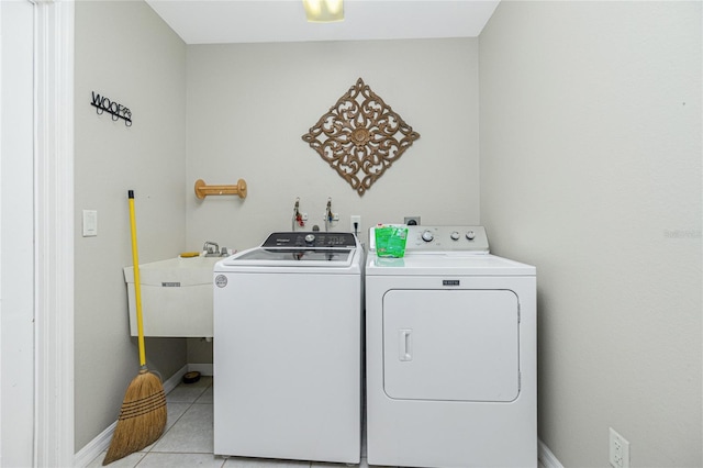 clothes washing area with light tile patterned floors, washer and dryer, and sink