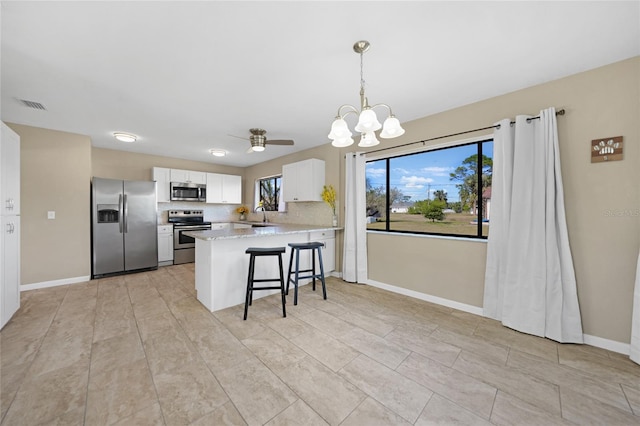 kitchen with a breakfast bar, white cabinetry, sink, kitchen peninsula, and stainless steel appliances