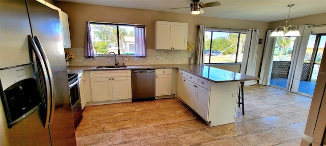 kitchen with sink, appliances with stainless steel finishes, white cabinets, decorative light fixtures, and kitchen peninsula