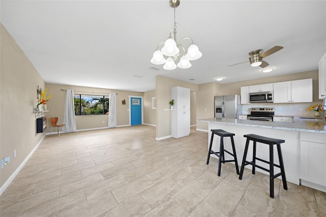 kitchen with sink, appliances with stainless steel finishes, a kitchen breakfast bar, light stone counters, and white cabinets