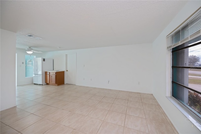 tiled empty room featuring a textured ceiling and ceiling fan