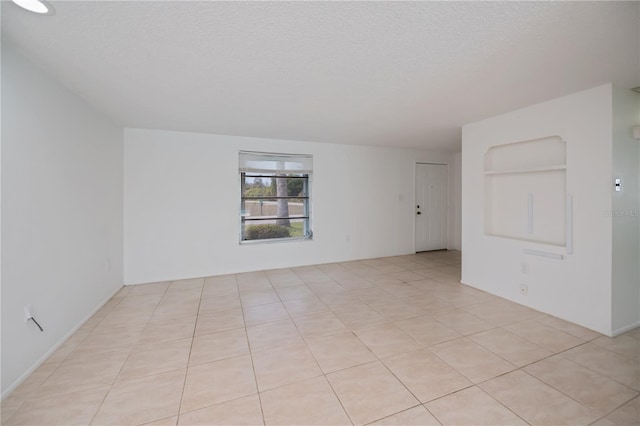 empty room with a textured ceiling and light tile patterned flooring