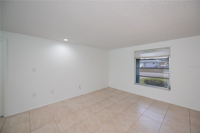 empty room with a textured ceiling and light tile patterned floors