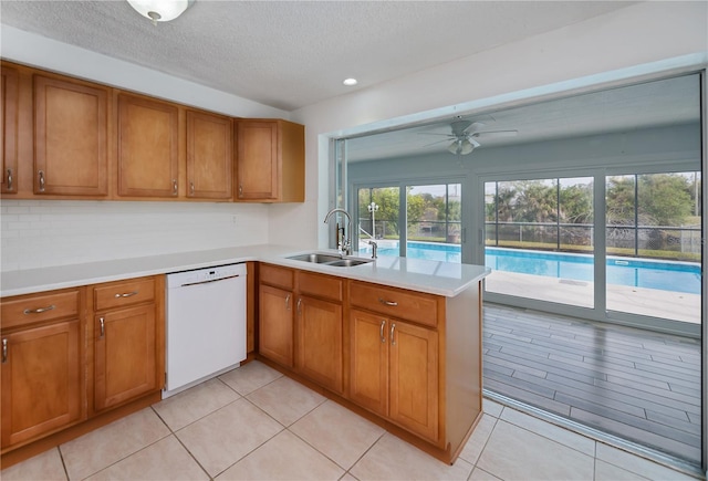 kitchen with ceiling fan, dishwasher, kitchen peninsula, sink, and light tile patterned flooring