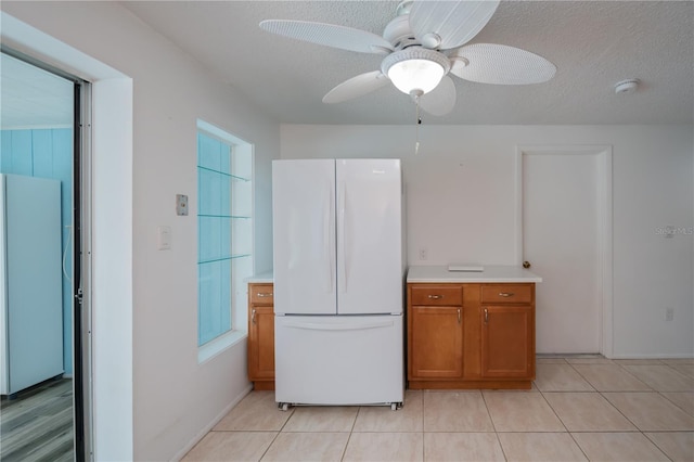 kitchen with ceiling fan, a textured ceiling, light tile patterned floors, and white refrigerator