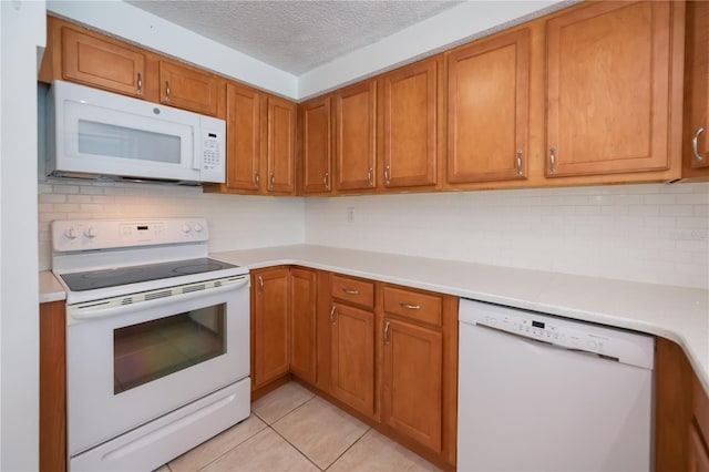 kitchen featuring light tile patterned floors, white appliances, and a textured ceiling