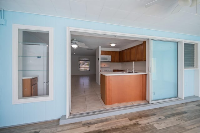 kitchen with ceiling fan, sink, white appliances, and light hardwood / wood-style flooring