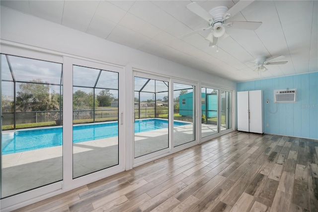 doorway to outside with ceiling fan, a wall mounted AC, and hardwood / wood-style floors