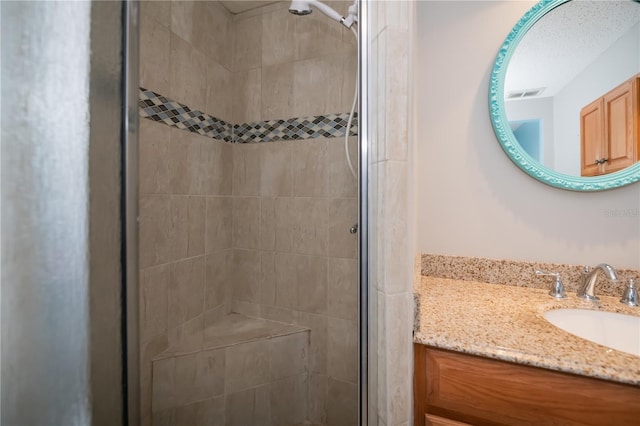 bathroom with a textured ceiling, an enclosed shower, and vanity