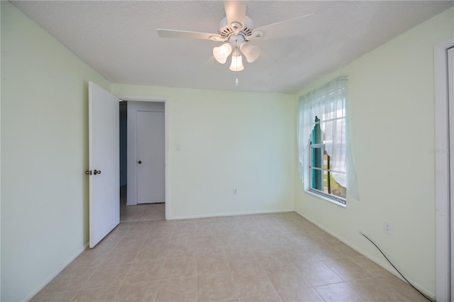 tiled empty room with ceiling fan and a textured ceiling