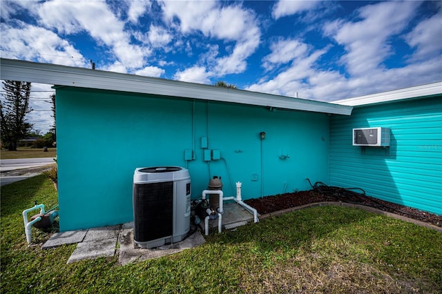 view of side of home featuring an AC wall unit, central AC unit, and a lawn