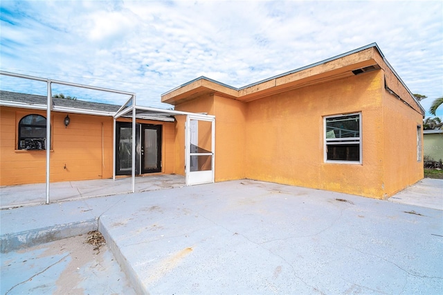 rear view of house featuring a patio area and stucco siding