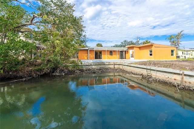 back of house with a water view and stucco siding