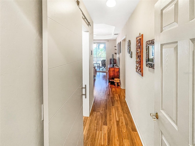 corridor with wood-type flooring and a barn door