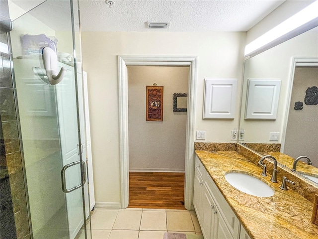 bathroom with vanity, tile patterned flooring, a textured ceiling, and a shower with door