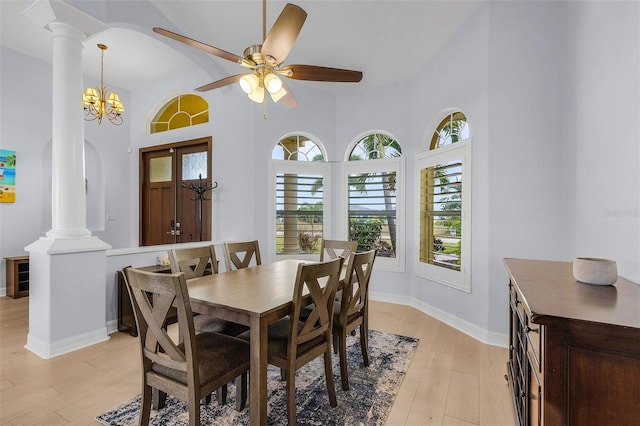 dining room featuring ornate columns, ceiling fan with notable chandelier, light hardwood / wood-style flooring, and high vaulted ceiling