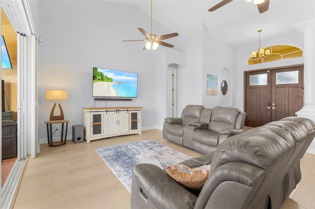 living room featuring vaulted ceiling, ceiling fan with notable chandelier, light hardwood / wood-style floors, and decorative columns