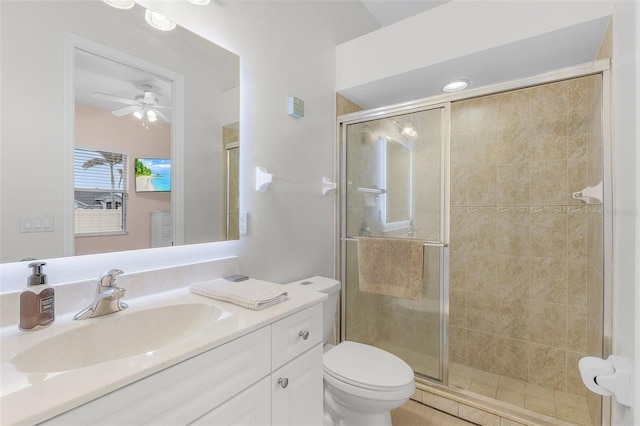 bathroom with walk in shower, vanity, ceiling fan, and toilet