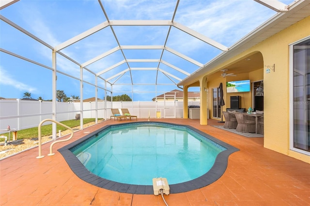 view of swimming pool with ceiling fan, a patio area, and glass enclosure