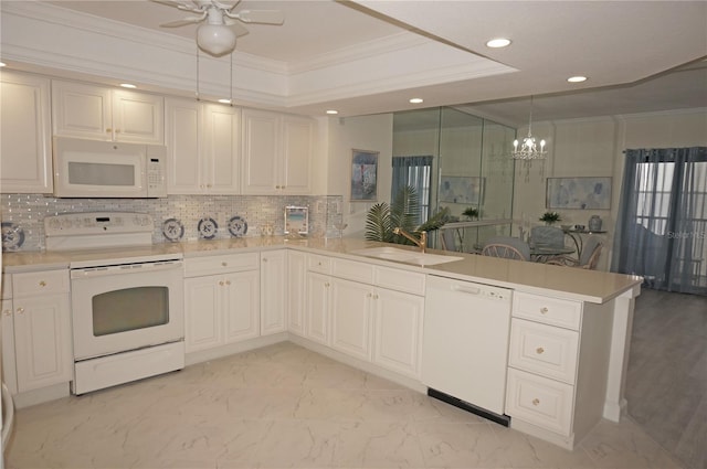 kitchen featuring kitchen peninsula, white appliances, hanging light fixtures, crown molding, and sink