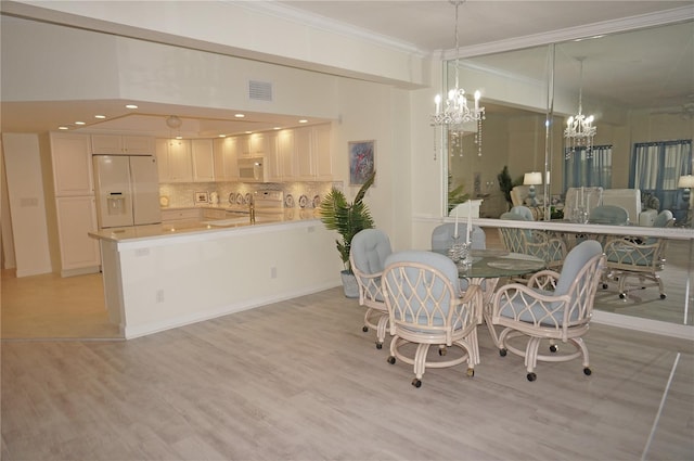 dining area with light hardwood / wood-style floors and ornamental molding