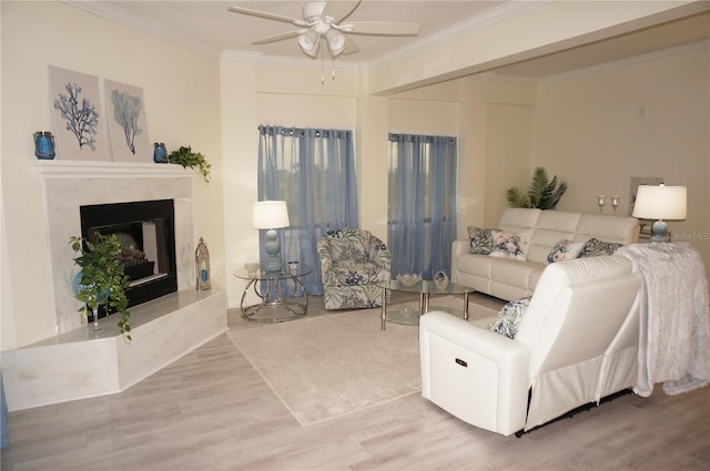 living room featuring ceiling fan, wood-type flooring, crown molding, and a premium fireplace