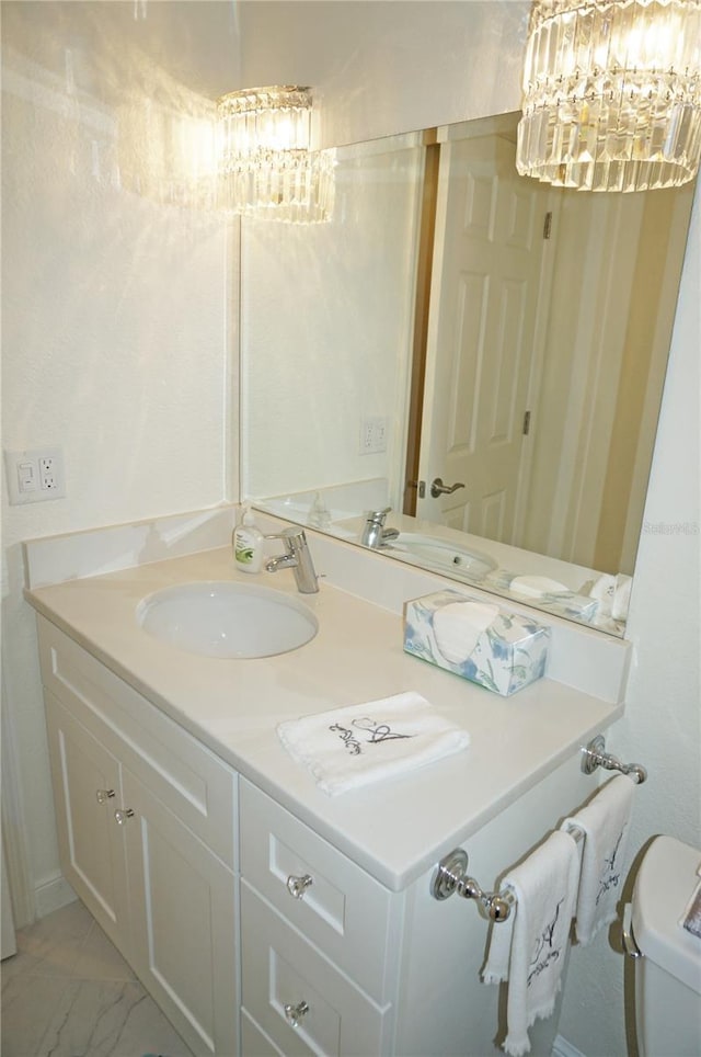 bathroom featuring toilet, vanity, and a notable chandelier