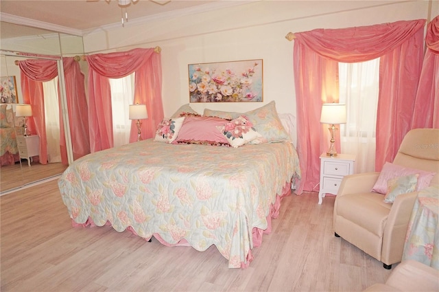 bedroom with light hardwood / wood-style floors, a closet, crown molding, and ceiling fan