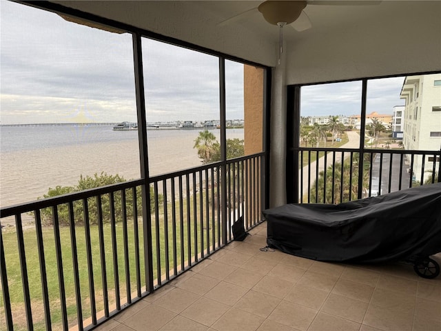 sunroom featuring a water view and ceiling fan