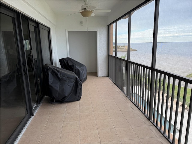 sunroom with ceiling fan and a water view