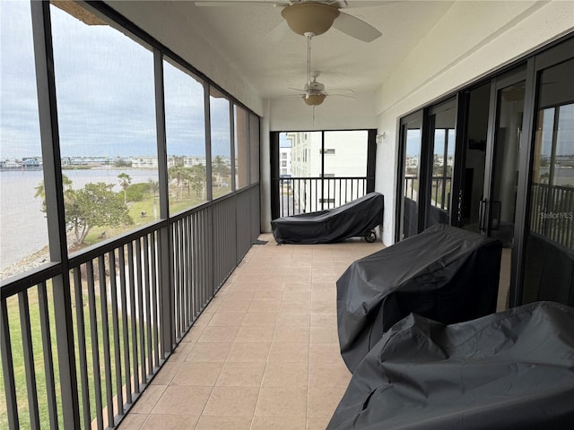 sunroom / solarium with ceiling fan and a water view