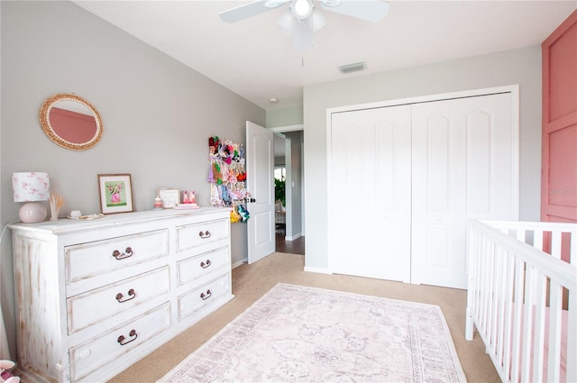 carpeted bedroom featuring ceiling fan, a nursery area, and a closet