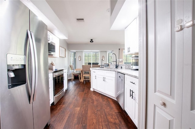 kitchen featuring kitchen peninsula, white cabinetry, dark wood-type flooring, light stone countertops, and appliances with stainless steel finishes