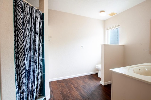 bathroom featuring hardwood / wood-style flooring, toilet, vanity, and walk in shower