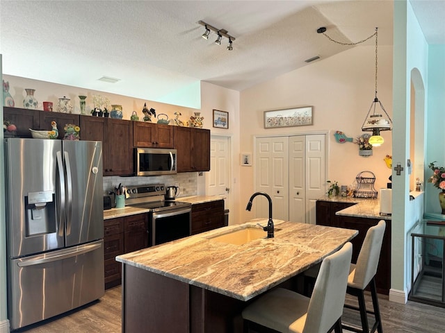 kitchen featuring wood-type flooring, light stone countertops, sink, and stainless steel appliances