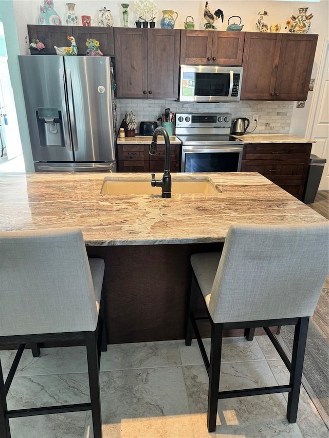 kitchen with backsplash, dark brown cabinetry, and appliances with stainless steel finishes