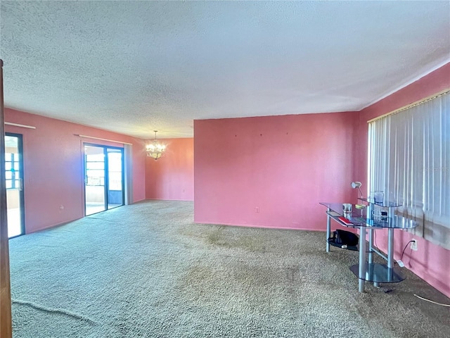 carpeted spare room featuring a textured ceiling and a notable chandelier